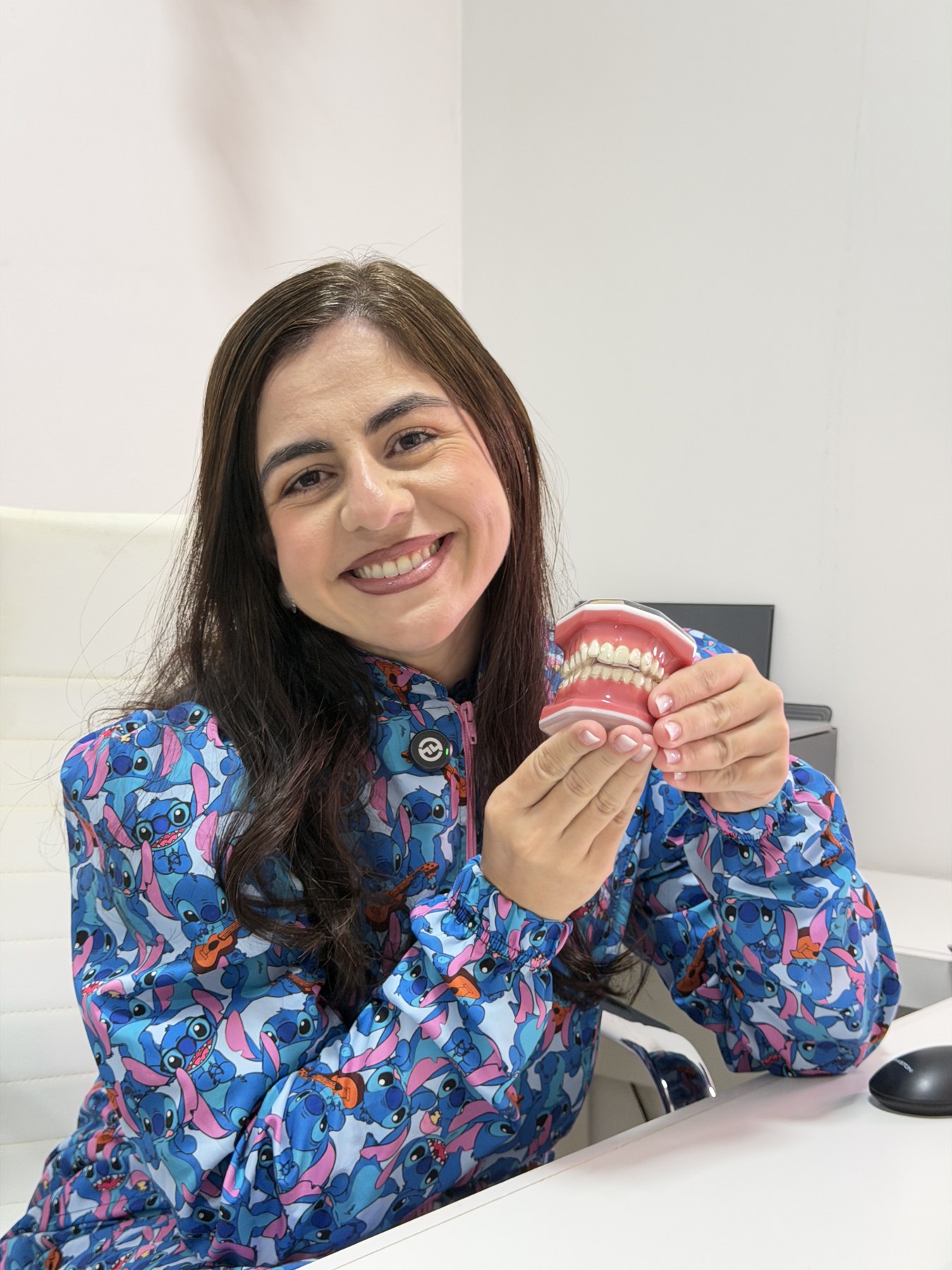 Dra. Iony Lopes Bispo sorrindo, segurando um modelo didático de dentes na clínica OdontoDreams em Vila Velha.